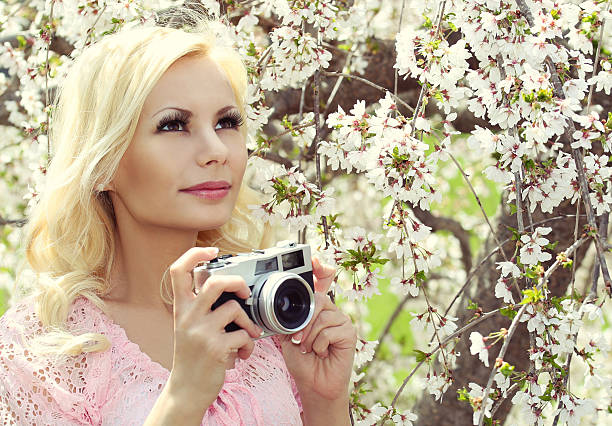 istock Blonde Girl with Retro Camera over Sakura. Cherry Blossom. 487963869