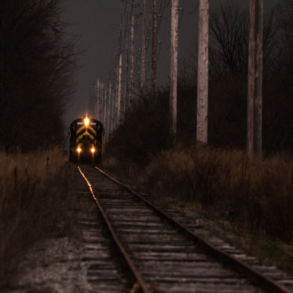 Train tracks at night by the platform with train approaching