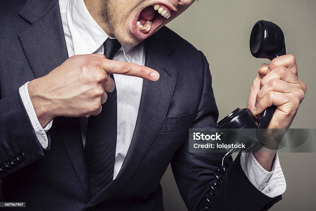 Angry businessman on the phone An angry young businesman is on the phone and screaming Adult Stock Photo