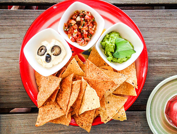 Close-up of nachos with carne asada beef and piled high with guacamole and other toppings.