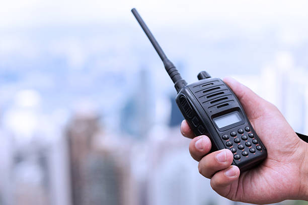 рука держит walky talky как фон с городской пейзаж - walkie talkie стоковые фото и изображения