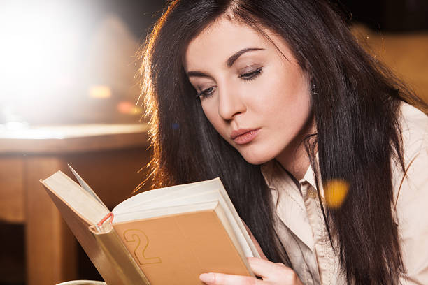 istock Woman lying on her couch reading a book at home 487971786