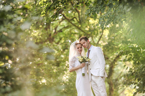 istock wedding couple holding hands in a park 487975382