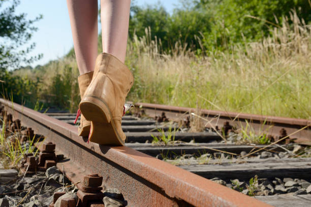 istock Girl legs in leather boots on rusty railroad track 487975646