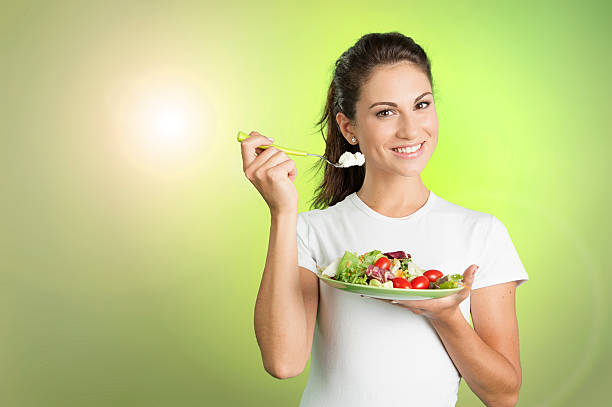 jovem mulher comer uma salada healty - healty imagens e fotografias de stock