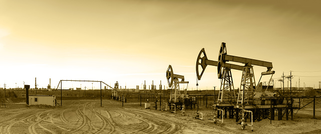Oil and gas industry. Panoramic of a pumpjack and oil refinery.