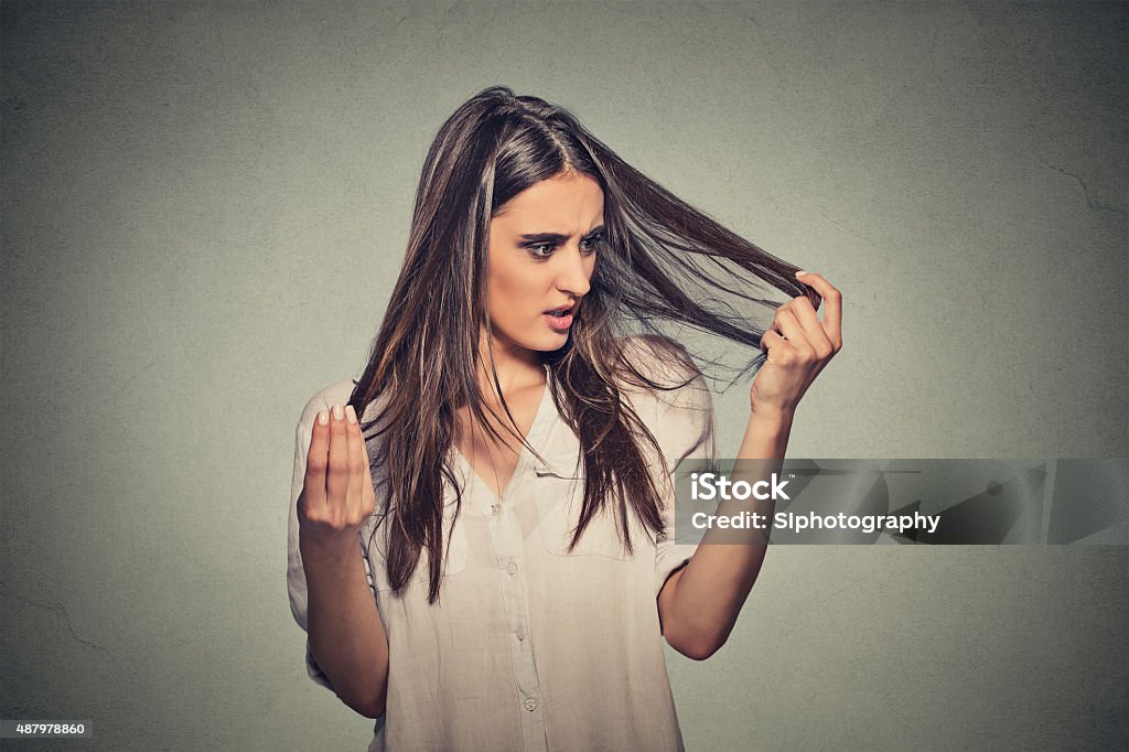 unhappy woman surprised she is losing hair Closeup unhappy frustrated young woman surprised she is losing hair, receding hairline. Gray background. Human face expression emotion. Beauty hairstyle concept Women Stock Photo