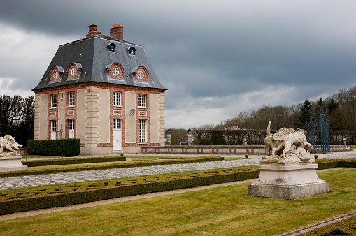Choisel, France -- April 4, 2015: Entrance building, statues, ornamental french garden and gate of the Breteuil Castle.