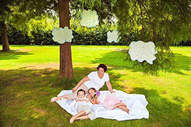 Grandmother with sleeping grandchildren under clouds in park