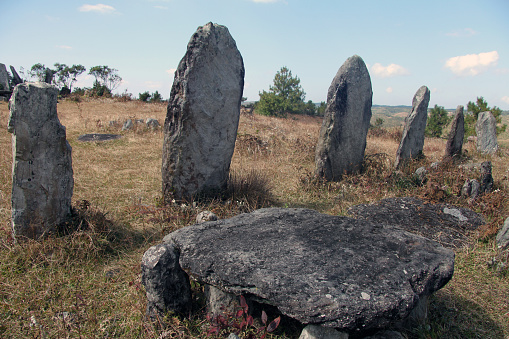 Several standing stones and a large round rock for sitting are on a hillside at Mawphlang sacred grove in Meghalaya, India