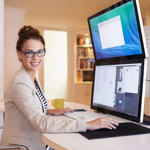 Portrait of a young woman working on a dual-screen computer at home