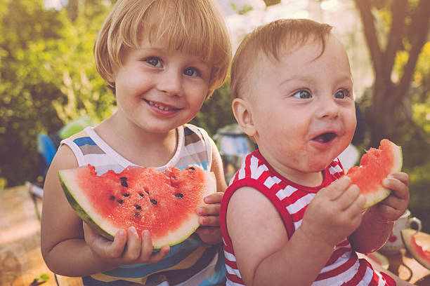 kinder mit wassermelone - sibling baby three people baby girls stock-fotos und bilder