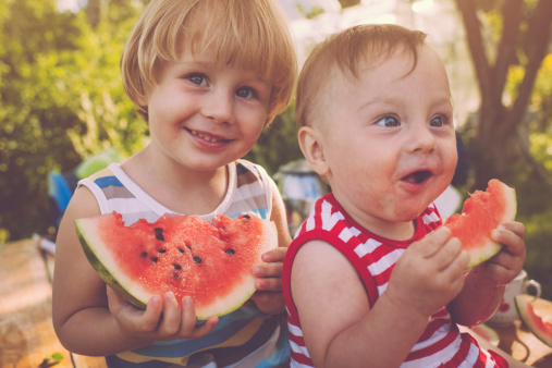 Happy brother and sister eating watermelon
