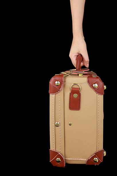istock Hand holding travel suitcase isolated on black 488004781
