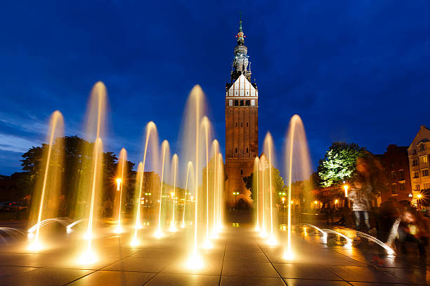Tower of Saint Nicholas Cathedral through illumination fountain in Elblag, Poland