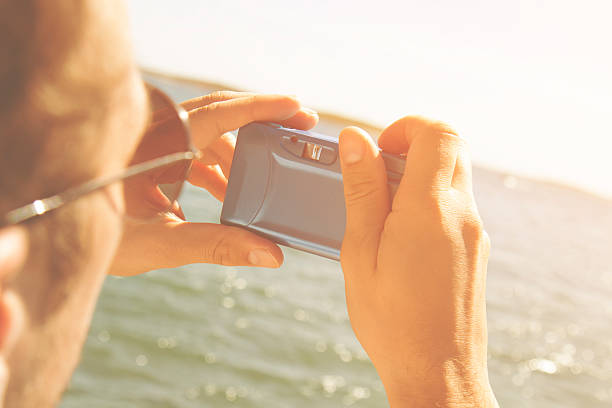 istock Hipster man taking photos with camera at the beach. 488010288