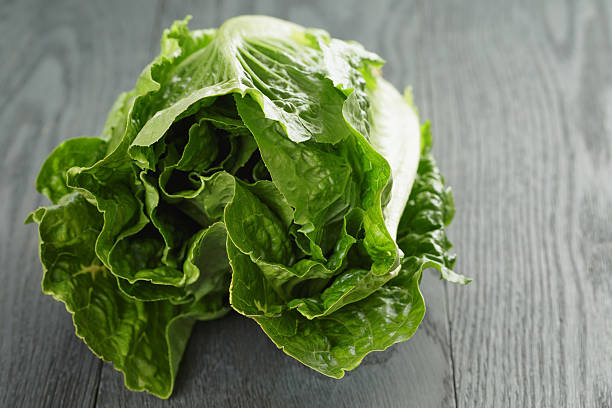 istock fresh romain green salad on wood table 488012374