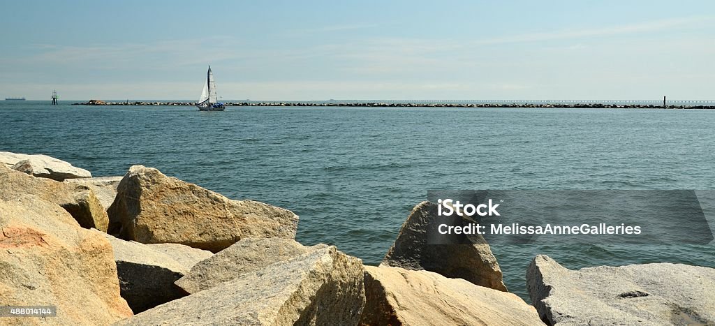 Rock Sea Wall Overlooking Chesepeake Bay Morning light illuminates a sailboat and sea wall stone chunks bordering a water chanel along the Chesapeake Bay. DSLR color image with copy space. 2015 Stock Photo