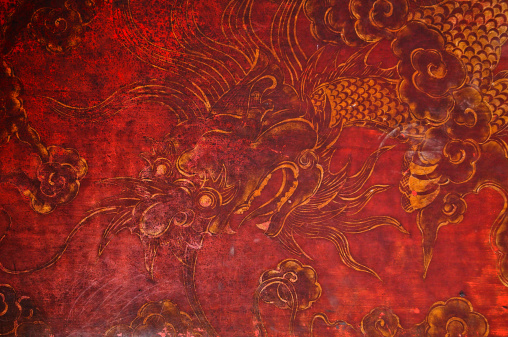 Ancient vintage golden painting of Chinese dragon on red wooden wall in the temple in Vietnam.