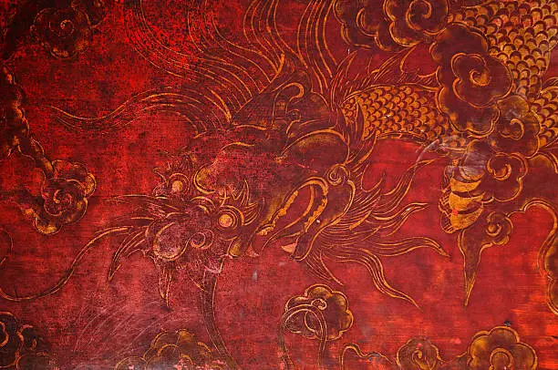 Ancient vintage golden painting of Chinese dragon on red wooden wall in the temple in Vietnam.