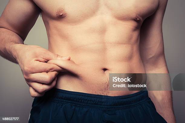 Fit Young Man Pinching His Stomach Stock Photo - Download Image Now - Liposuction, Men, Abdominal Muscle