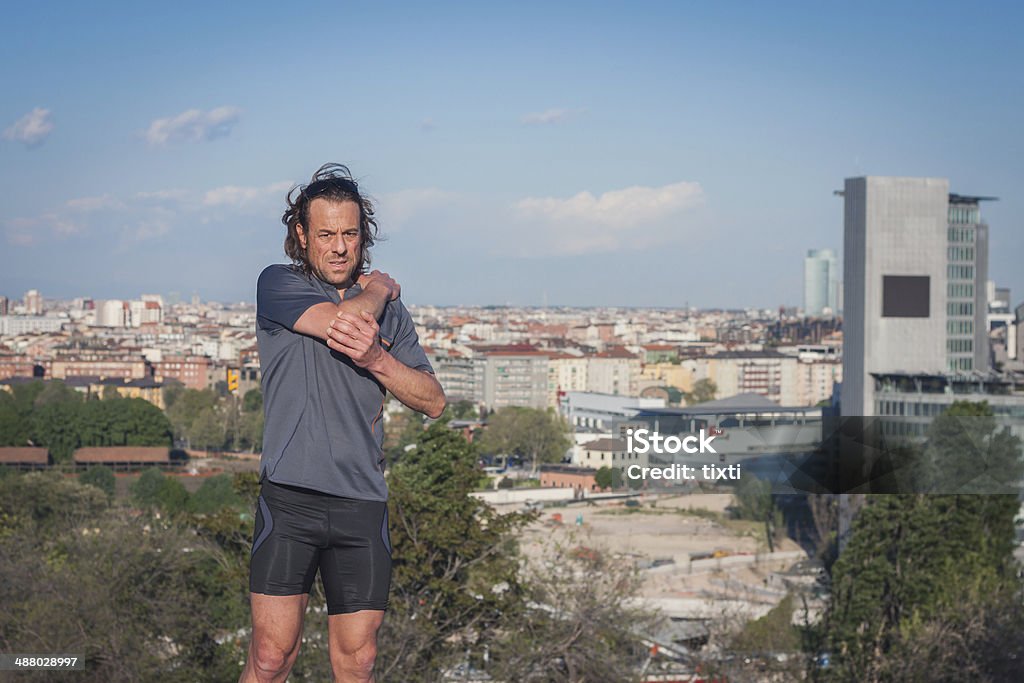Long haired athlete stretching in a city park Mature long haired athlete stretching in a city park Active Lifestyle Stock Photo