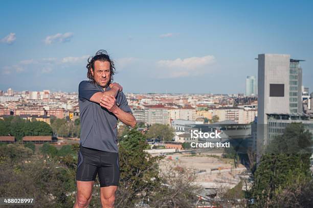 Long Haired Athlete Stretching In A City Park Stock Photo - Download Image Now - Active Lifestyle, Activity, Adult