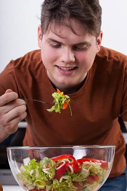 Portrait of young happy man eating salad