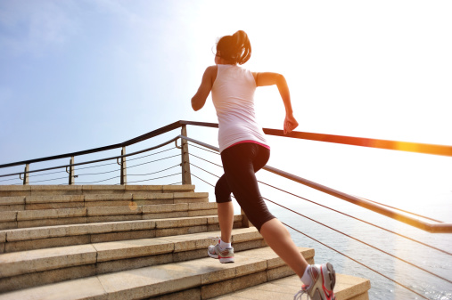 Runner athlete running at seaside stone stairs. woman fitness jogging workout wellness concept.