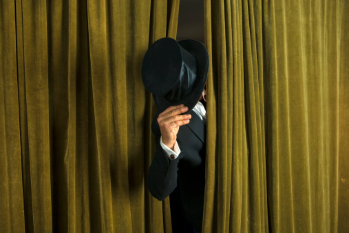 Theatre: Actor with opera hat appears from behind the curtain.