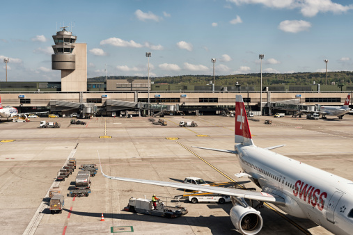 Zurich, Switzerland - April 16, 2014:  View to the main building of airport Zurich with two Swiss and one Edelweiss airplane waiting for boarding