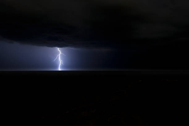 Lightning strike over the Tasman Sea, Australia A huge fork strikes and lights up the horizon after a massive storm drifts out over the Tasman Sea, Australia high energy physics stock pictures, royalty-free photos & images