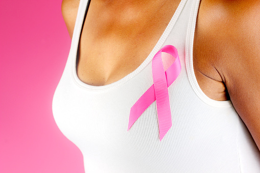Black woman wearing the symbol of breast cancer awareness month, October