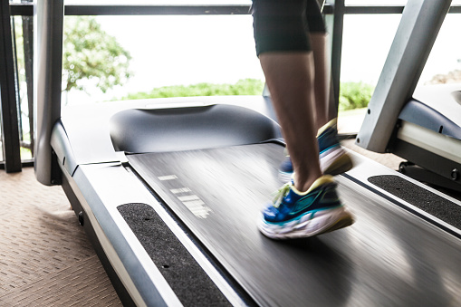 Woman Exercising in Gym running on treadmill