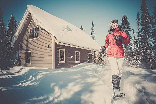 donna camminare con le racchette e chalet in legno nella neve farinosa - winter snowshoeing running snowshoe foto e immagini stock