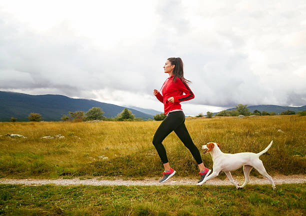 mujer joven con su perro para trotar - corredora de footing fotografías e imágenes de stock