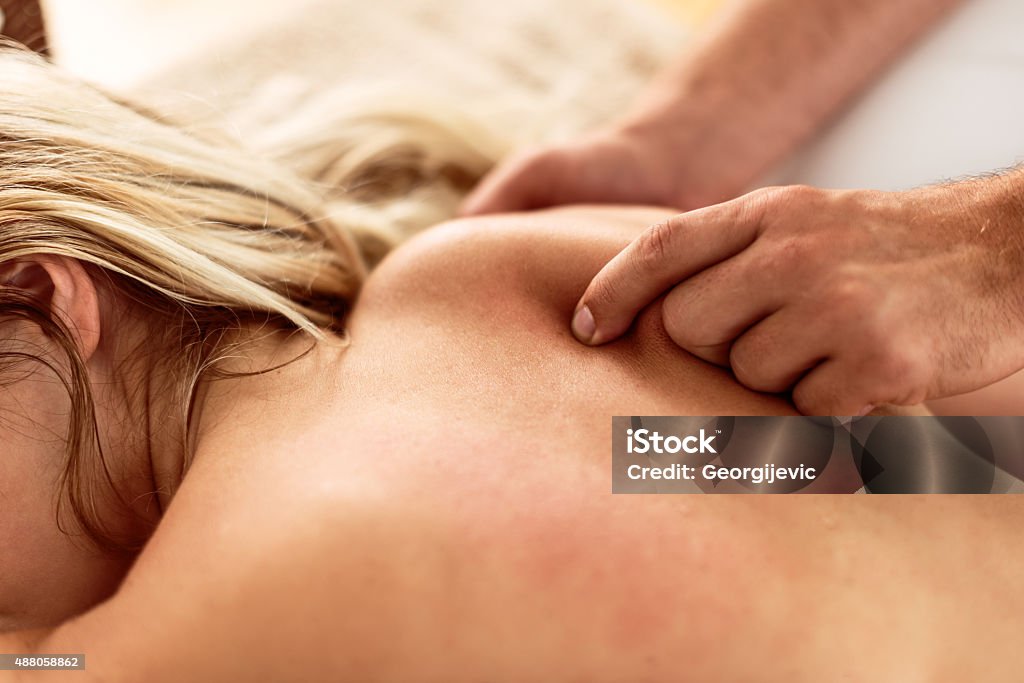 Receiving a shoulder blade massage Closeup of a pretty young woman receiving shoulder blade massage. 2015 Stock Photo