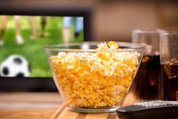 Watching soccer game on television at pub or home. Popcorn.