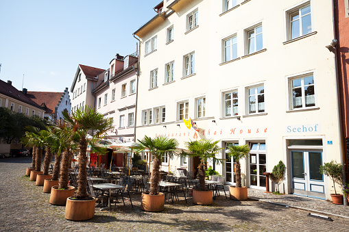 Lindau, Germany - July 11, 2015: View alog pedestrian zone of Lindau island in summer. In one of buildings is Thai restaurant. Outside are palm trees.