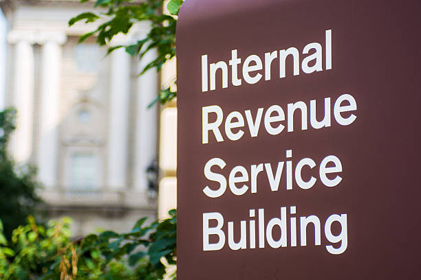 Internal Revenue Service (IRS) Building in Washington, DC Washington, United States - August 18, 2014: A sign saying "Internal Revenue Service Building" stands outside the Internal Revenue Service (IRS) building. The IRS is responsible for collecting taxes in the United States as well as the administration of the Internal Revenue Code and has 89,500 employees. Annually, it collects approximately $2.4 trillion in taxes.  IRS Headquarters Building stock pictures, royalty-free photos & images