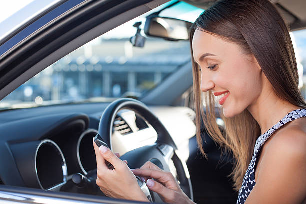 istock Cheerful young woman is using telephone in car 488064162