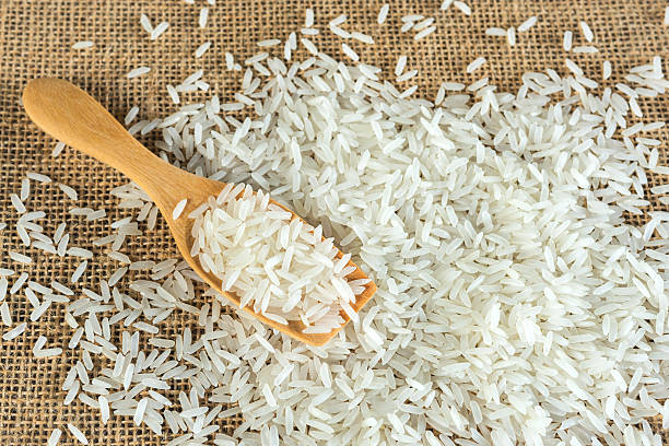 istock Jasmine rice with wooden spoon on textile background 488066570