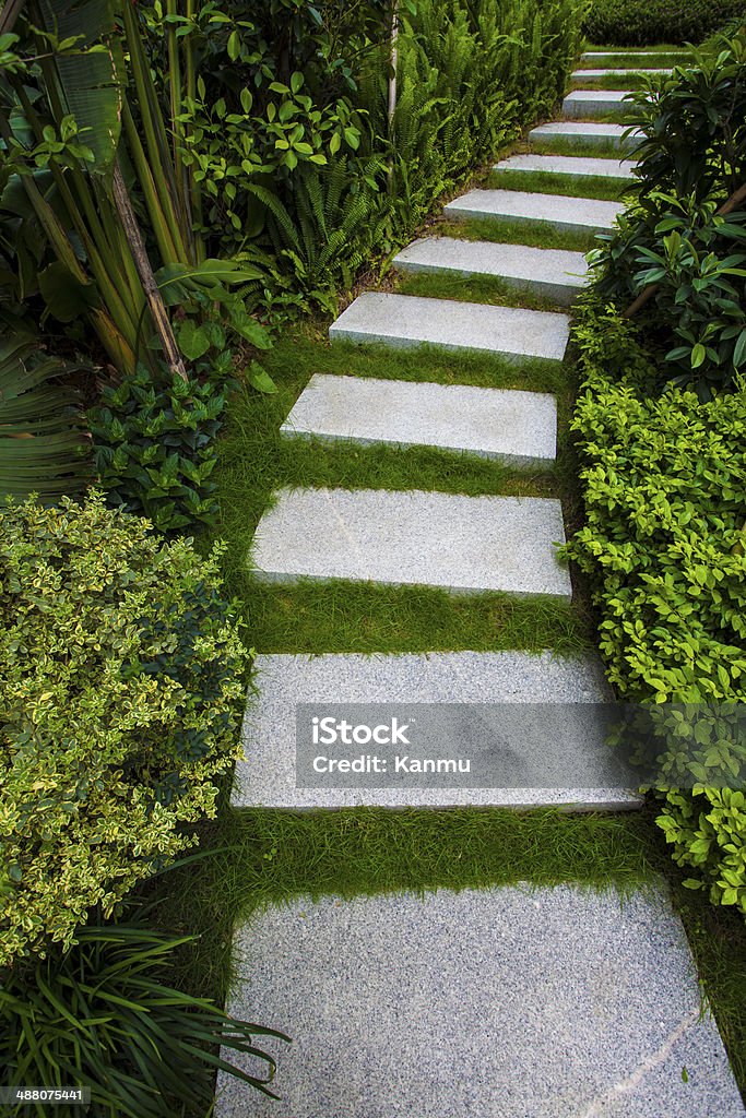 Vialetto di pietra avvolgimento la sua strada attraverso tranquillo giardino - Foto stock royalty-free di A forma di blocco