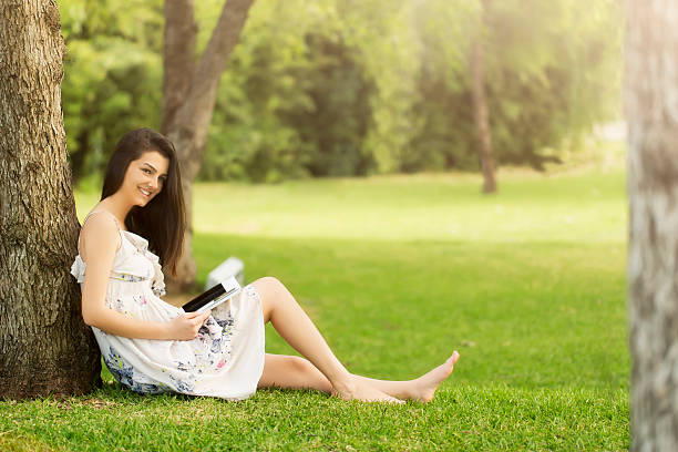 istock Relaxed, young woman reading book on green grass 488076321