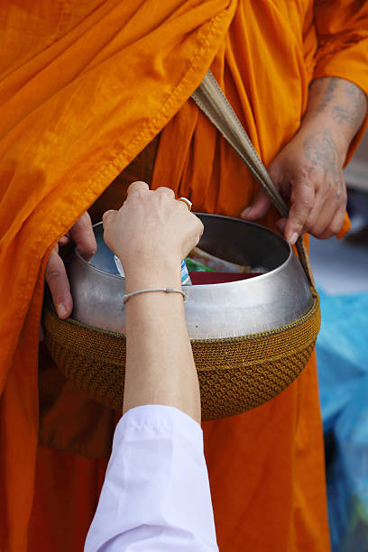 istock Hand put food offerings in a Buddhist monk's alms bowl 488077321