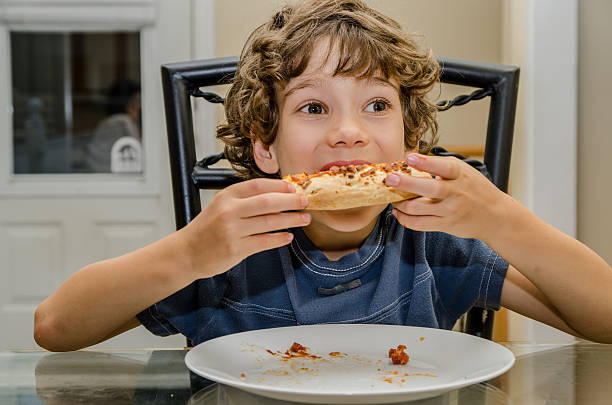 istock Boy eating slice of pizza in white plate 488080356