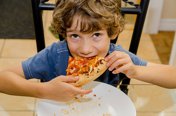 istock Boy eating slice of pizza in white plate 488080416