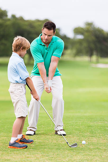 маленький мальчик принимая уроки pro для инструктора - golf golf swing putting cheerful стоковые фото и изображения