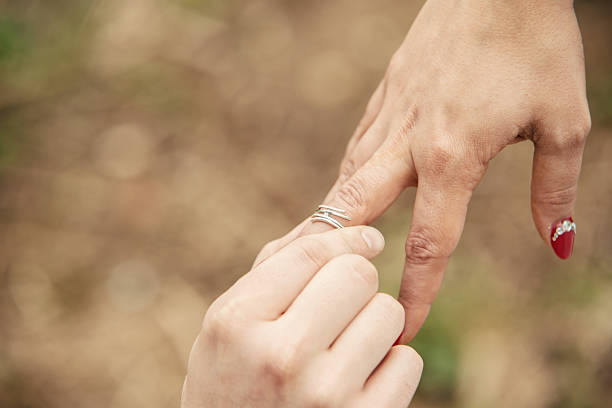 istock Groom putting a wedding ring on bride's finger 488082241
