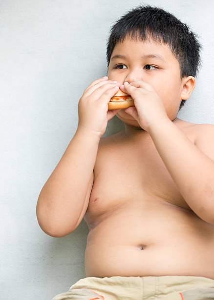 istock obese fat boy child eat chicken hamburger 488086264
